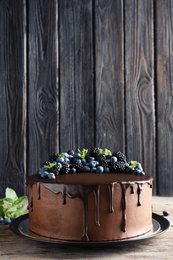 Photo of Fresh delicious homemade chocolate cake with berries on table against wooden background