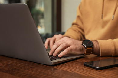 Photo of Male blogger working with laptop at table in cafe, closeup