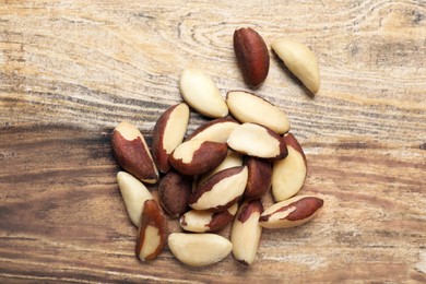 Photo of Heap of delicious Brazil nuts on wooden table, top view