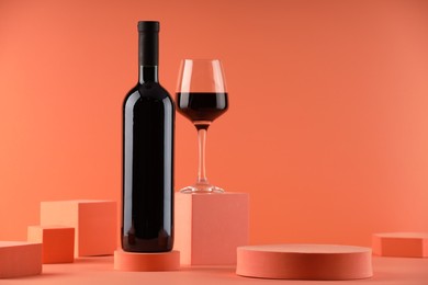 Photo of Stylish presentation of delicious red wine in bottle and glass on orange background. Space for text