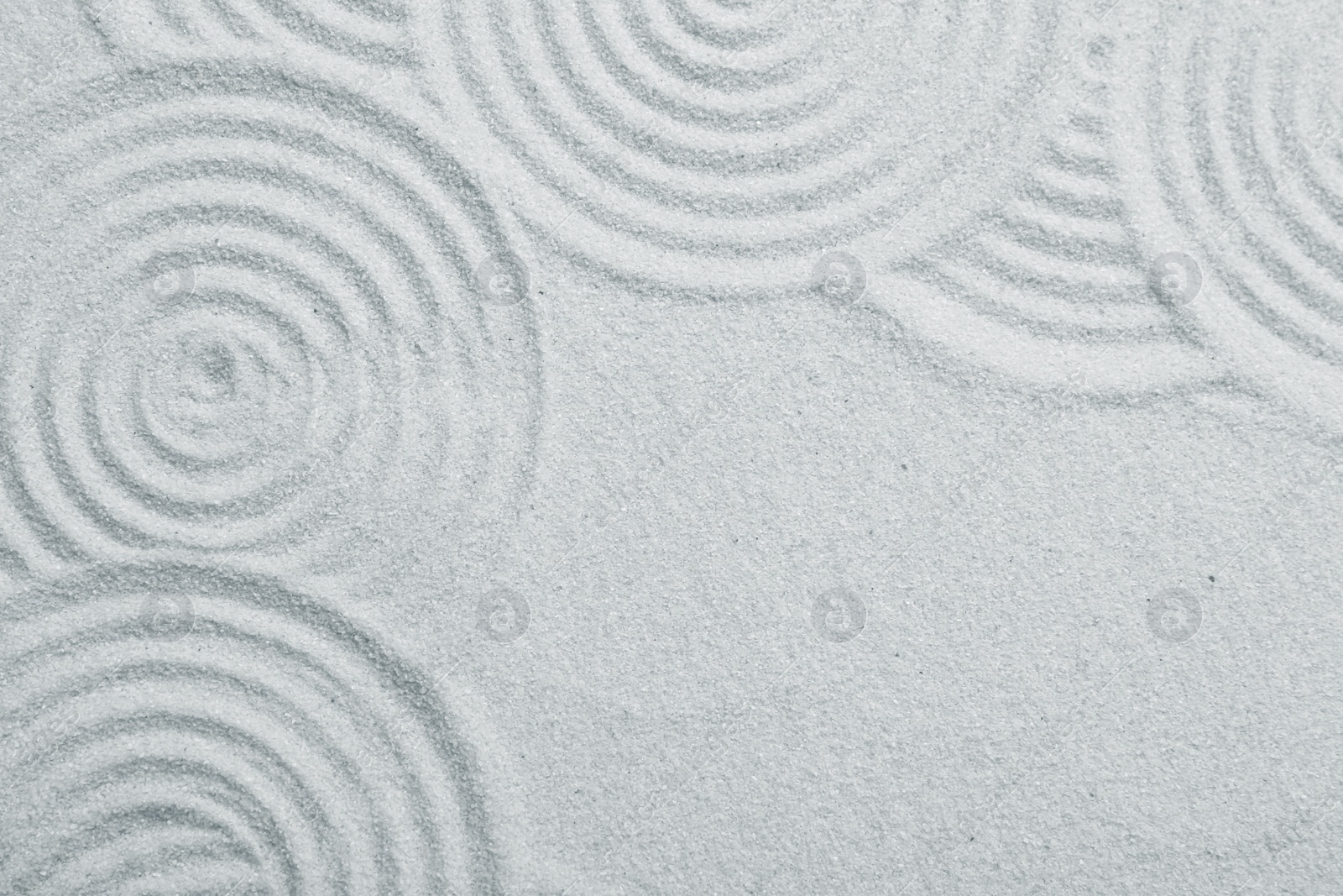 Photo of Zen rock garden. Circle patterns on white sand, top view