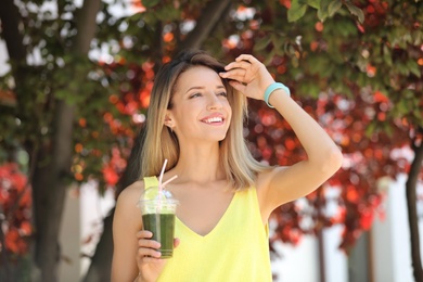 Young woman with plastic cup of healthy smoothie outdoors