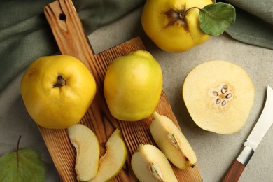 Photo of Tasty ripe quince fruits and knife on grey table, flat lay