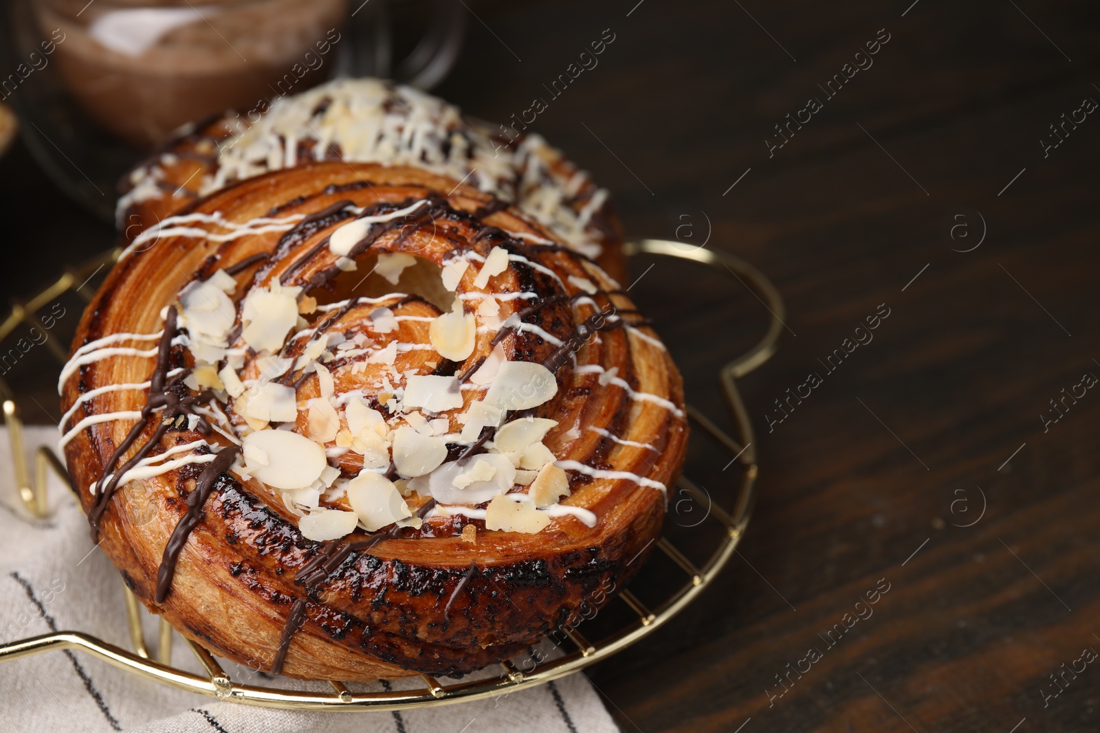 Photo of Sweet buns. Delicious rolls with toppings and almond on wooden table, closeup. Space for text