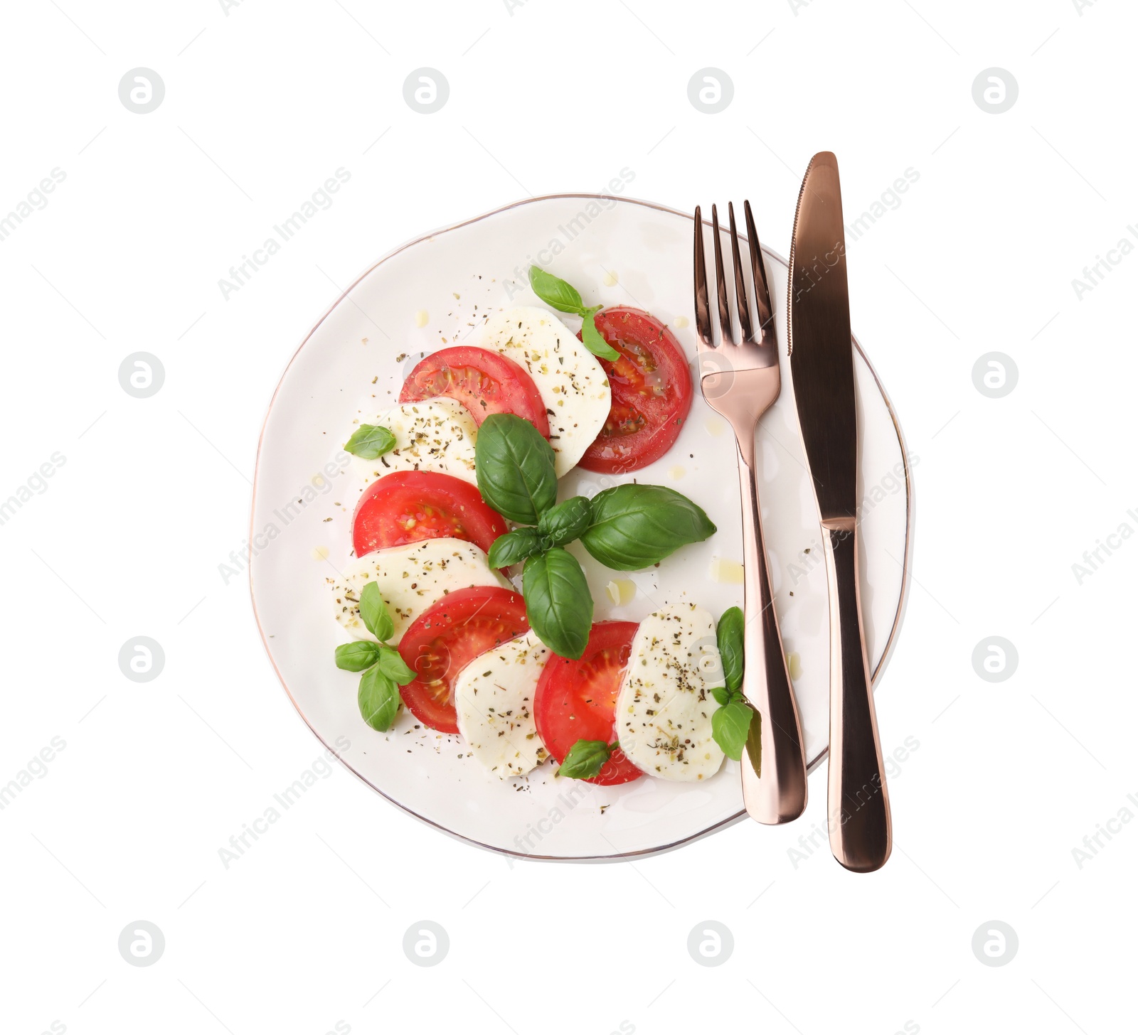 Photo of Plate of delicious salad Caprese with tomatoes, mozzarella, basil, spices and cutlery isolated on white, top view