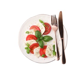 Plate of delicious salad Caprese with tomatoes, mozzarella, basil, spices and cutlery isolated on white, top view