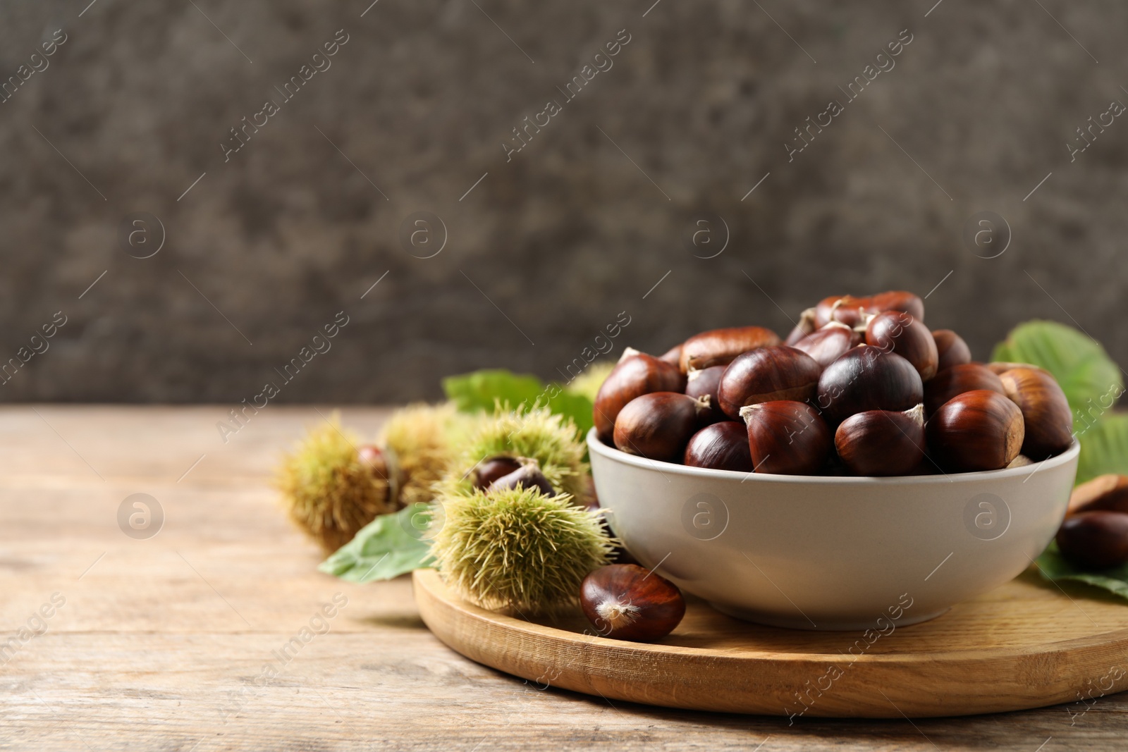 Photo of Fresh sweet edible chestnuts on wooden table. Space for text