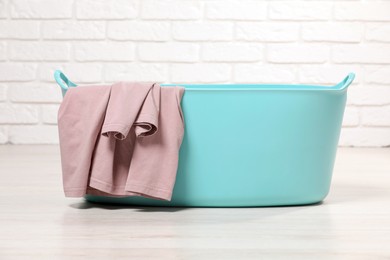Laundry basket with clothes near white brick wall