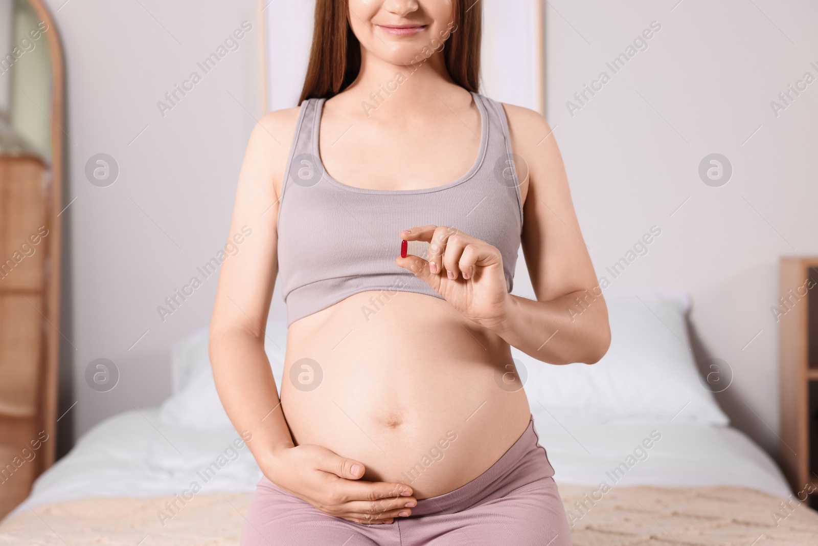 Photo of Pregnant woman taking pill at home, closeup