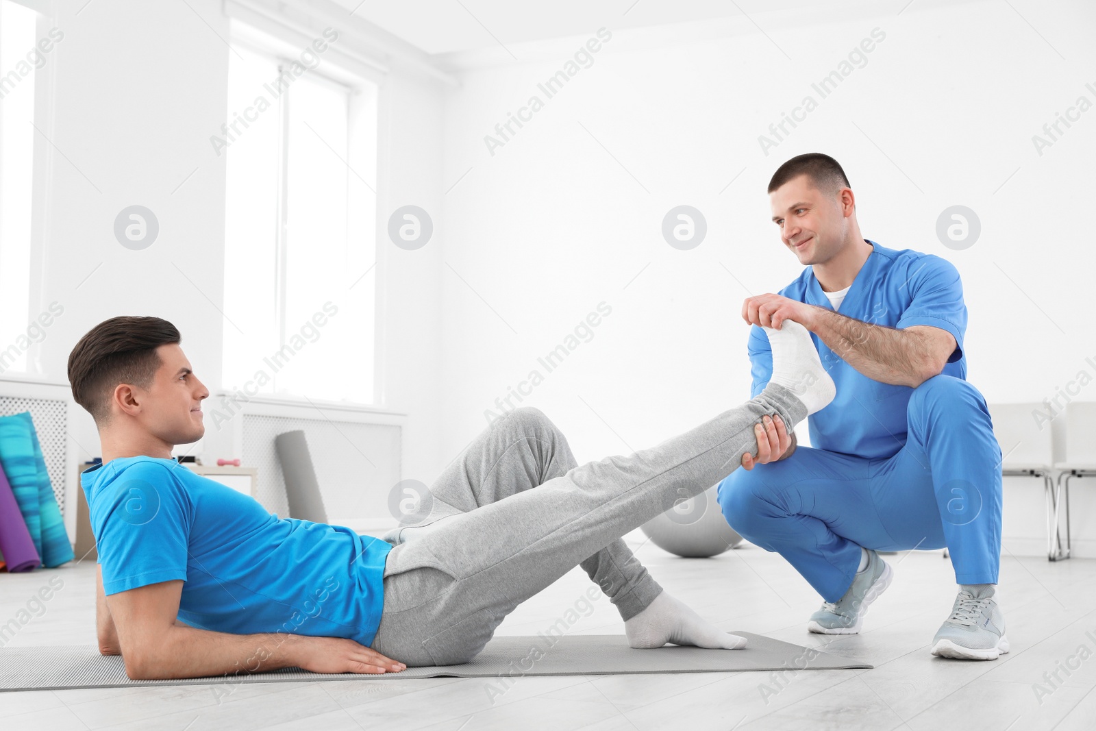 Photo of Professional physiotherapist working with male patient in rehabilitation center
