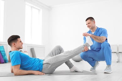 Photo of Professional physiotherapist working with male patient in rehabilitation center