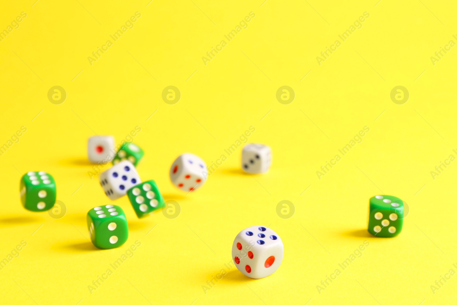 Photo of Many color game dices falling on yellow background