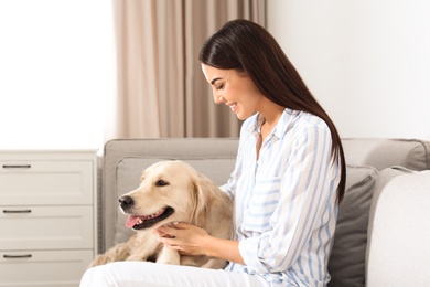 Photo of Young woman and her Golden Retriever dog in living room