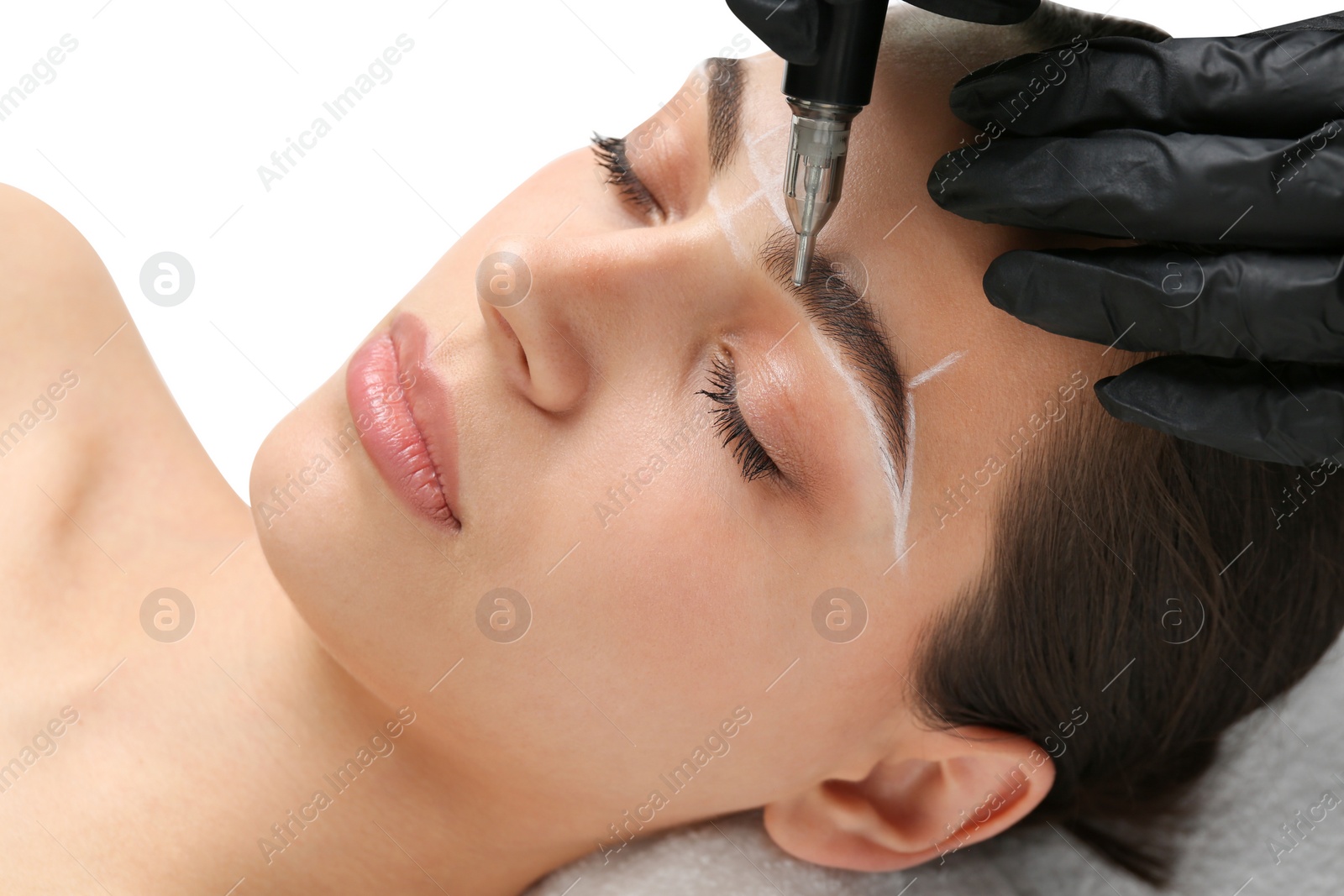 Photo of Beautician making permanent eyebrow makeup to young woman on white background, closeup