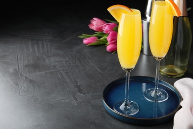 Photo of Glasses of Mimosa cocktail with garnish on grey table. Space for text