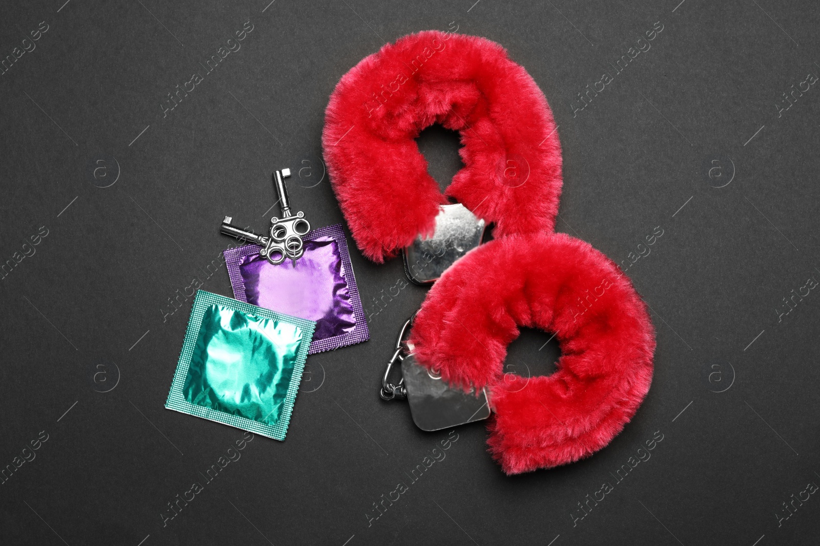 Photo of Furry handcuffs and condoms on black background, top view. Sex game