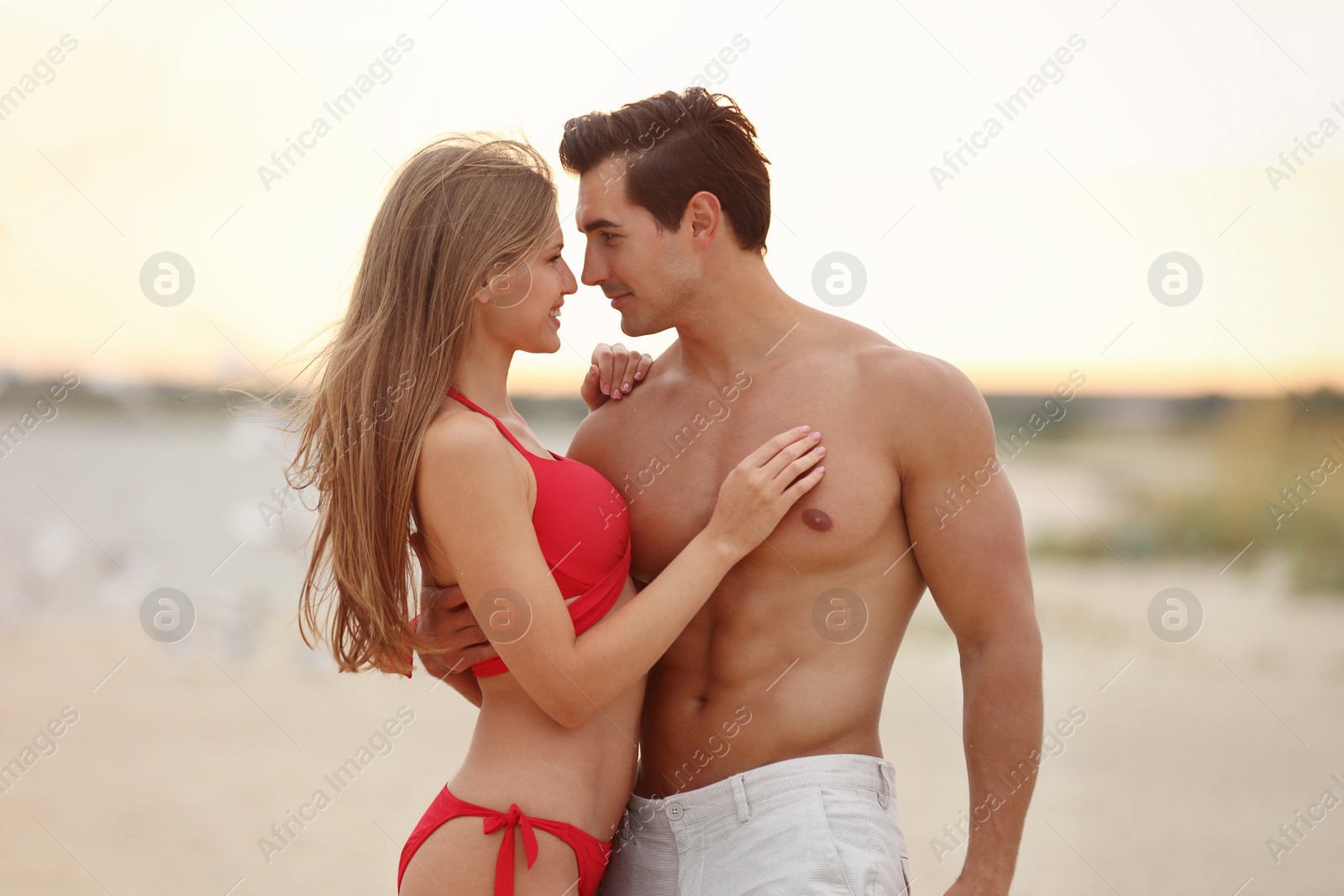 Photo of Happy young couple spending time together on sea beach at sunset