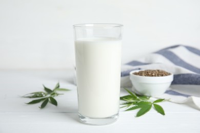 Glass of fresh hemp milk on white wooden table