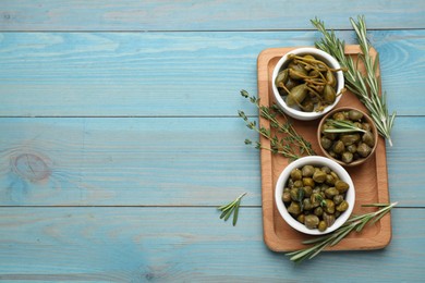 Tasty capers, thyme and rosemary on light blue wooden table, flat lay