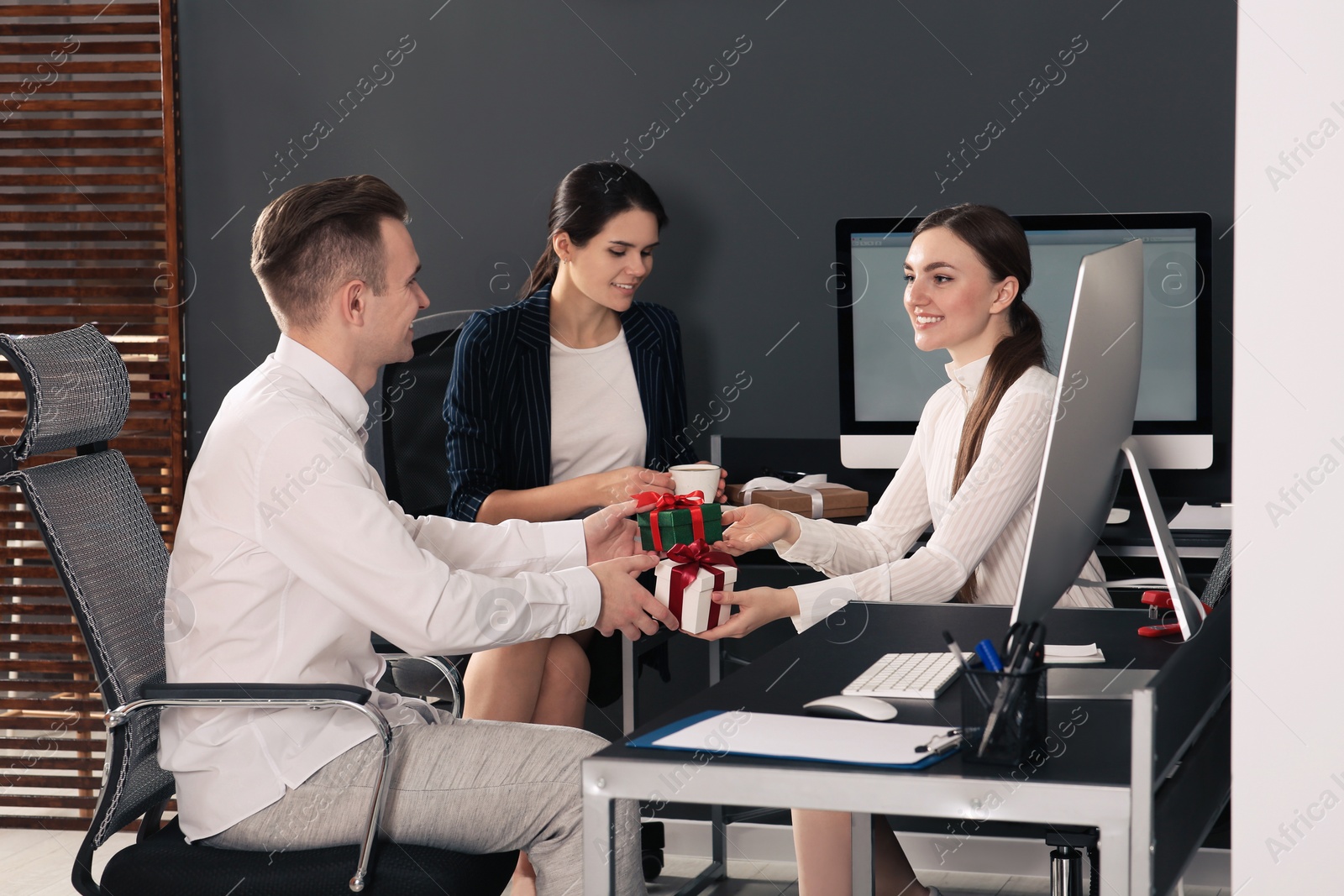 Photo of Colleagues presenting gifts each other in office