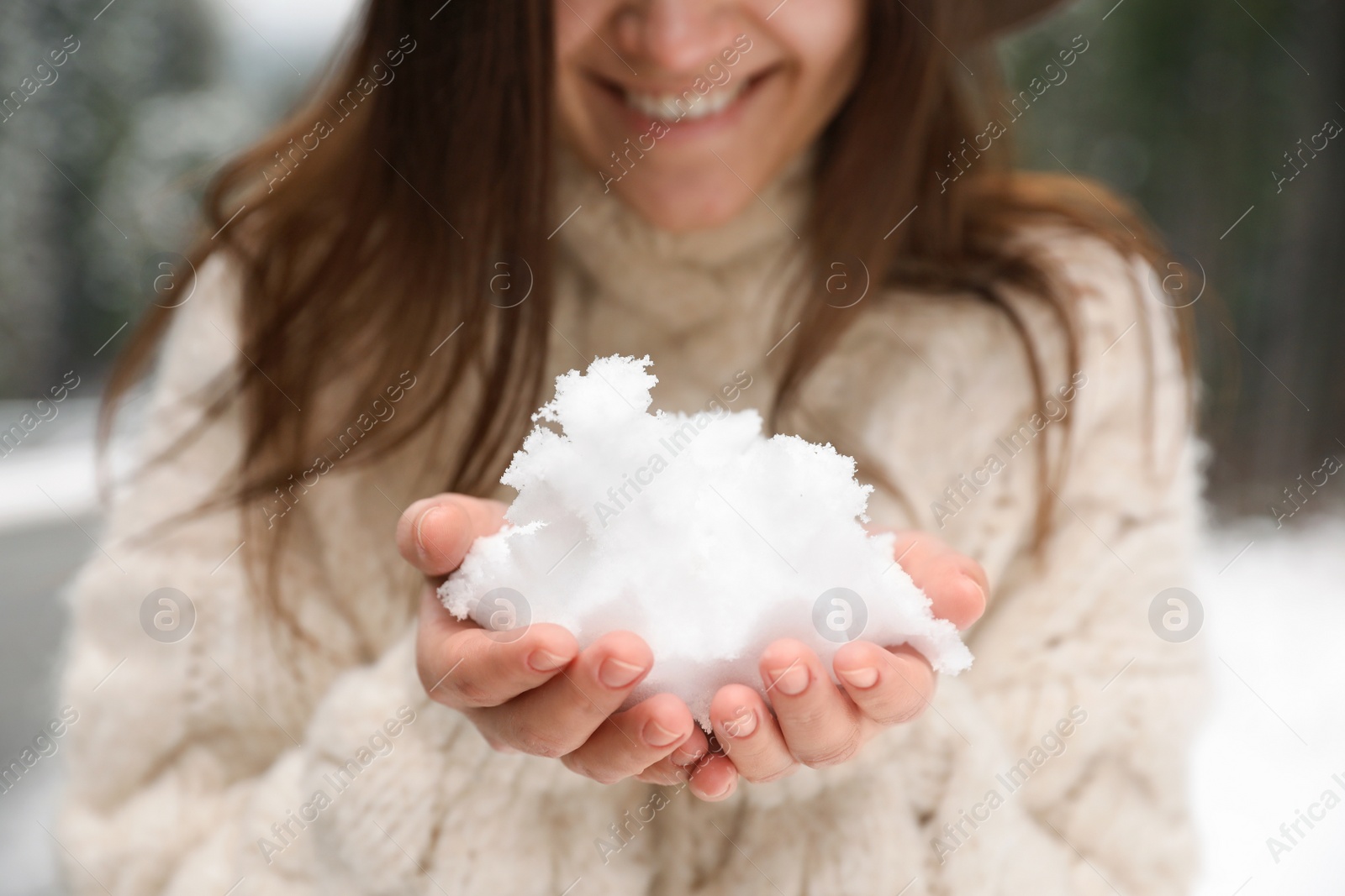 Photo of Young woman holding snow outdoors, closeup. Winter vacation