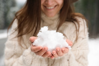 Young woman holding snow outdoors, closeup. Winter vacation