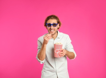 Photo of Emotional man with 3D glasses and popcorn during cinema show on color background