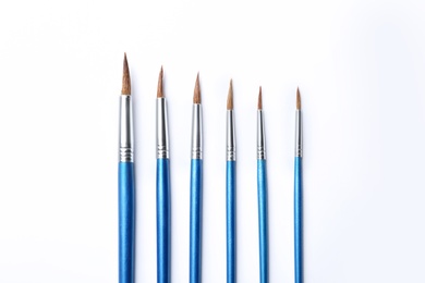 Photo of Different paint brushes on white background, top view