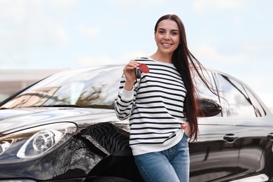 Woman holding car flip key near her vehicle outdoors