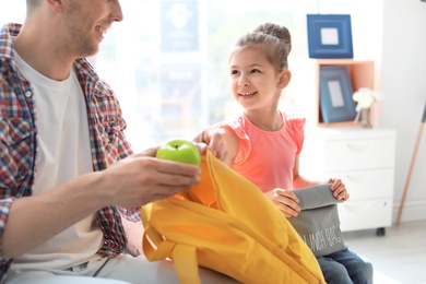 Photo of Young man helping his little child get ready for school at home