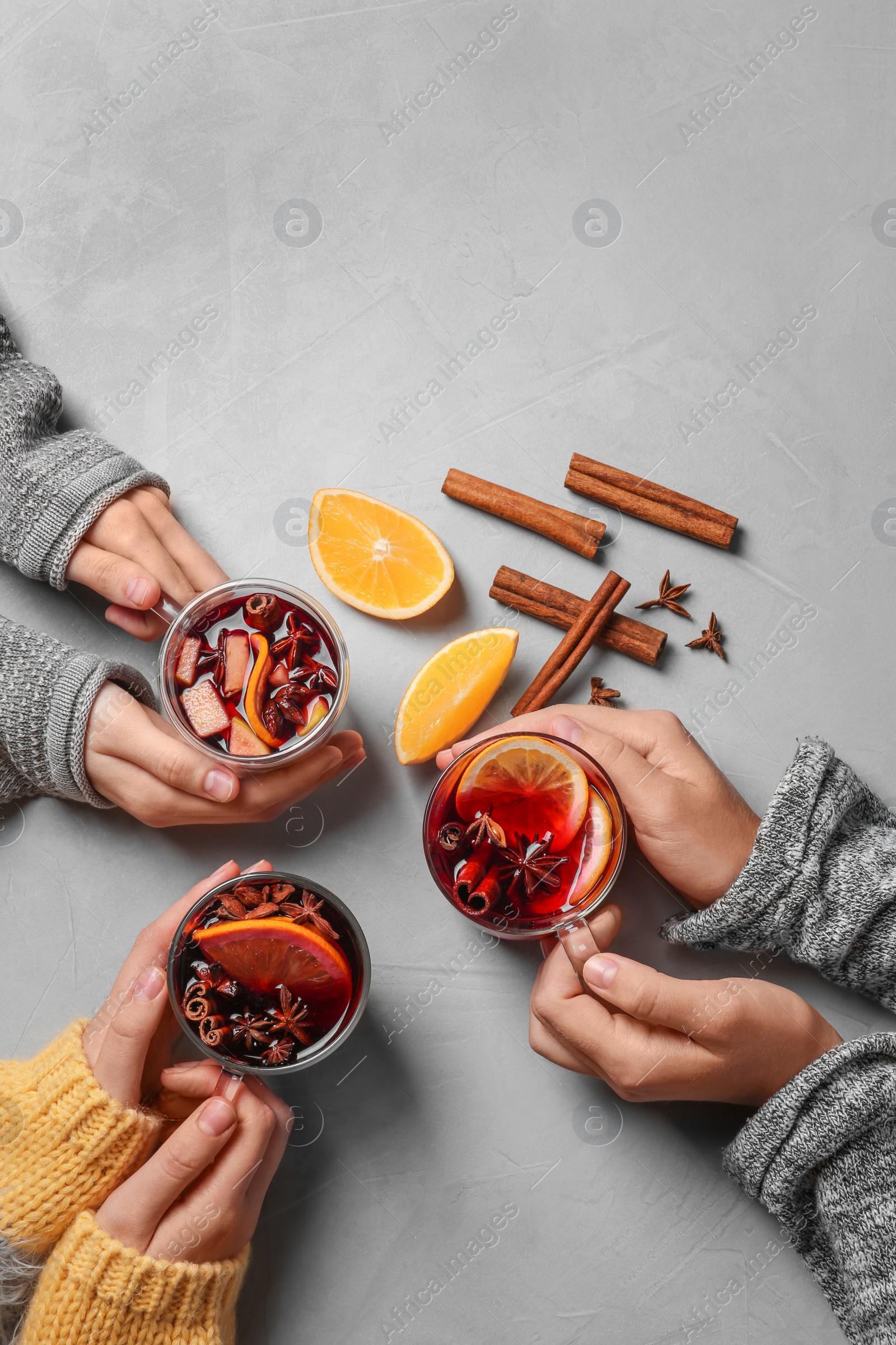 Photo of Women holding cups with hot mulled wine on table, top view