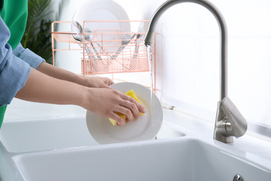 Woman washing plate in modern kitchen, closeup