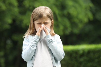 Photo of Little girl suffering from seasonal spring allergy outdoors, space for text