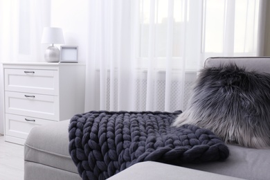 Photo of Knitted merino wool blanket on sofa in room. Interior design