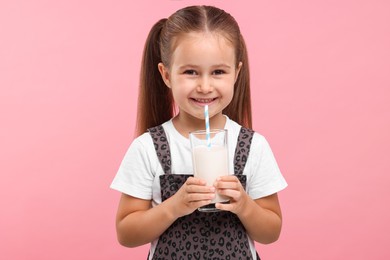 Photo of Cute girl with glass of fresh milk on pink background