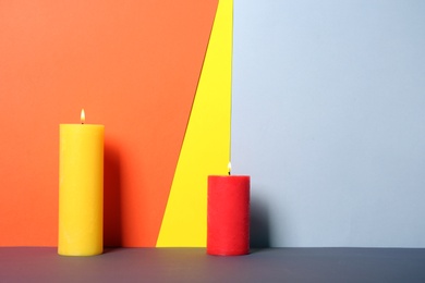 Photo of Decorative candles on table against color background