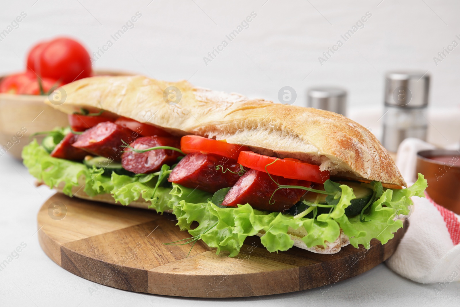 Photo of Delicious sandwich with sausages and vegetables on white table, closeup