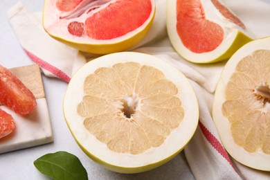 Different tasty pomelo fruits on white textured table, closeup