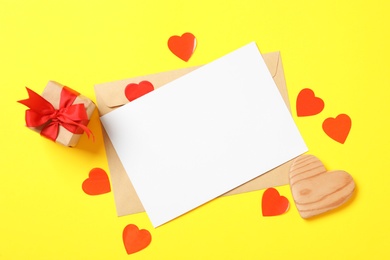 Photo of Flat lay composition with blank card on yellow background, space for text. Valentine's Day celebration