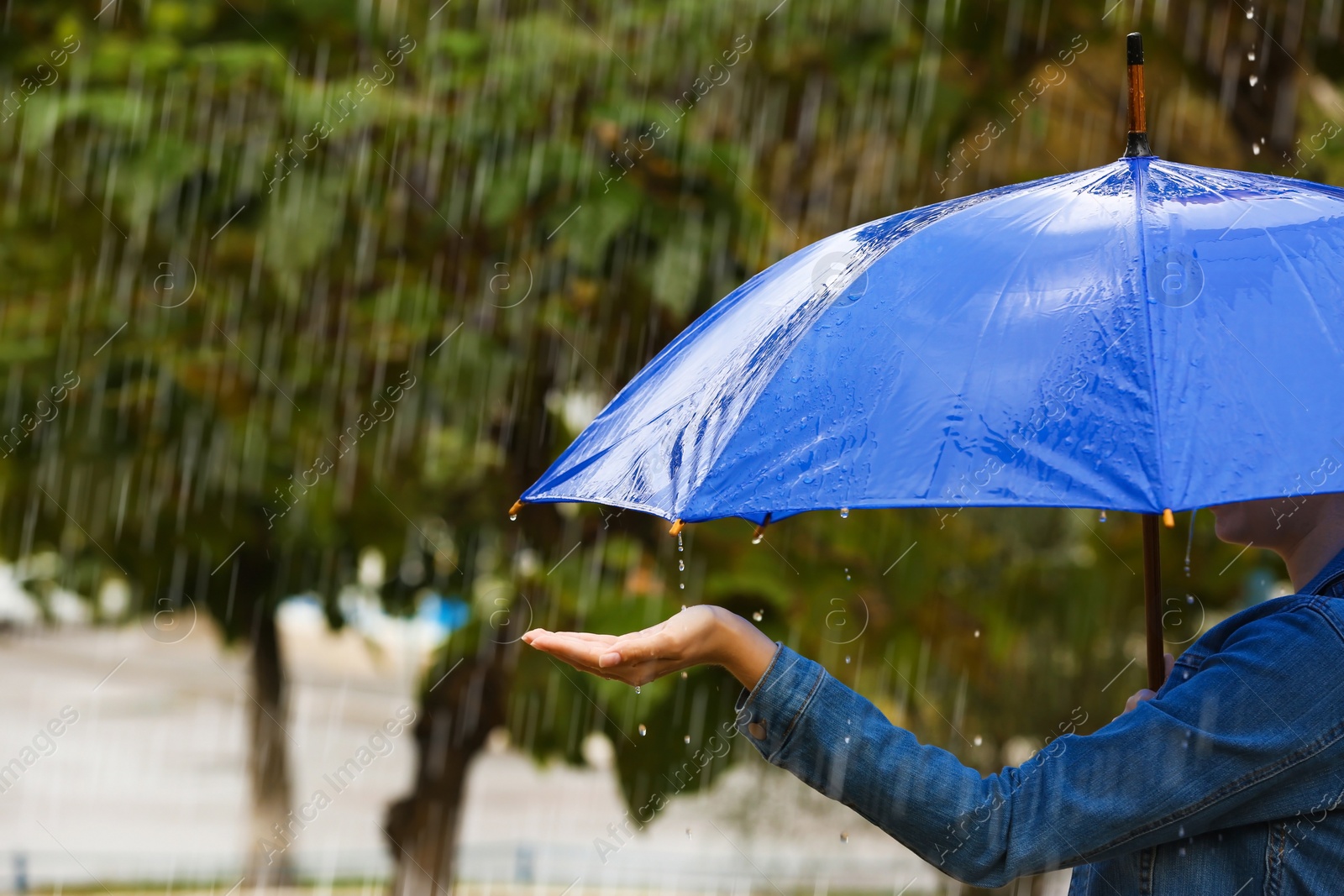 Photo of Woman with bright umbrella under rain on street, closeup