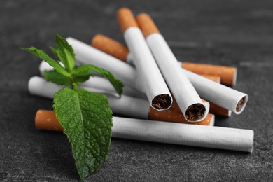Photo of Menthol cigarettes and mint on grey table, closeup