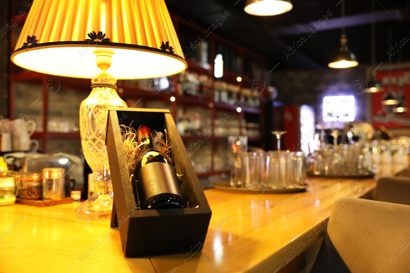 Photo of Wooden box with bottle of wine on counter in bar, space for text