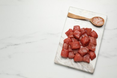 Cooking delicious goulash. Raw beef meat and sea salt on white marble table, top view. Space for text