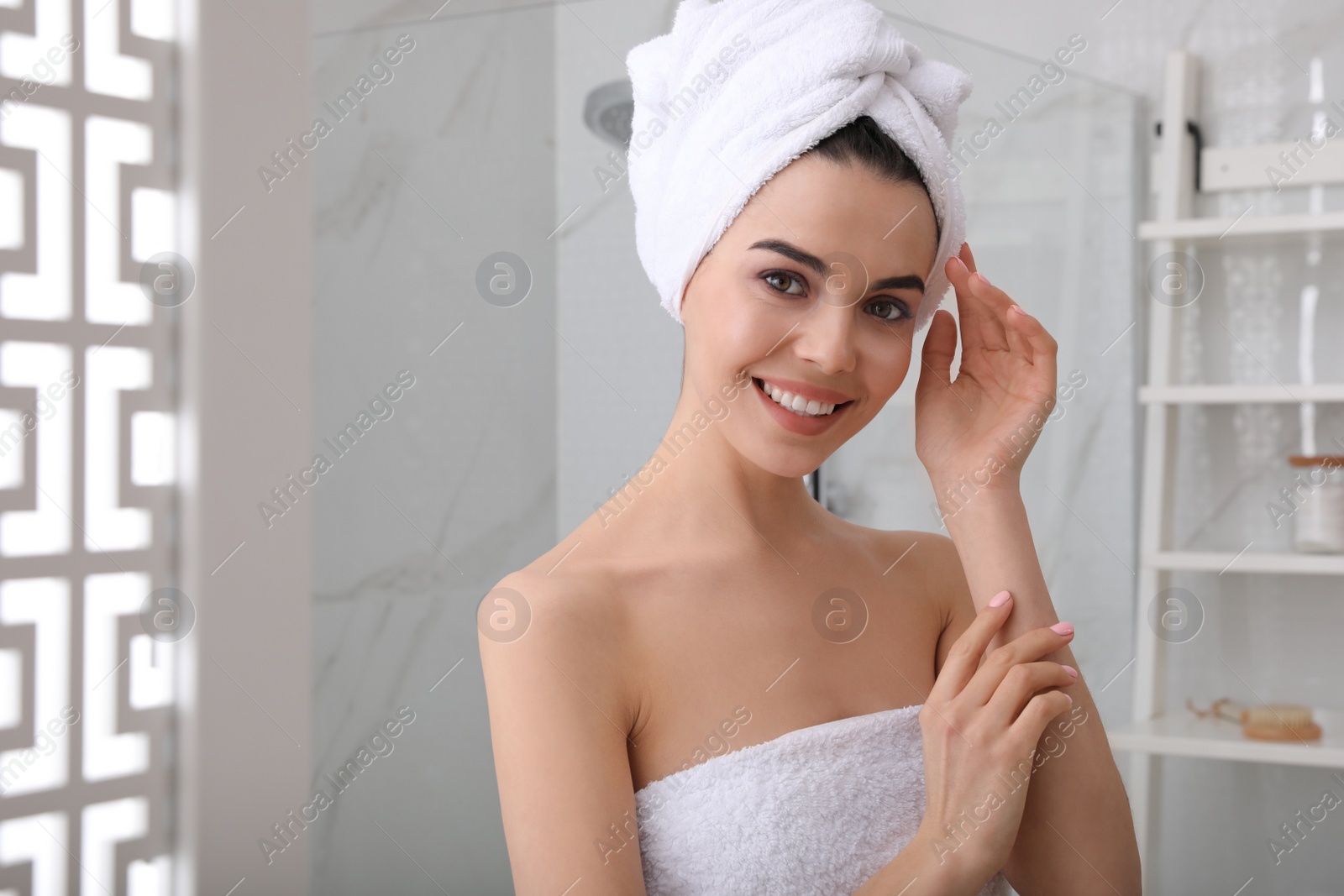 Photo of Happy young woman with towel on head in bathroom, space for text. Washing hair