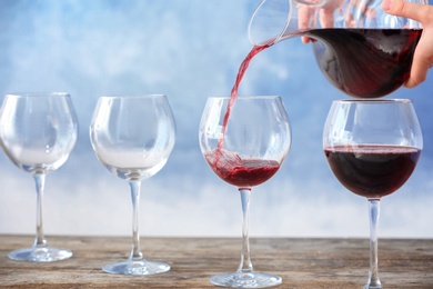 Photo of Pouring delicious red wine into glass on table