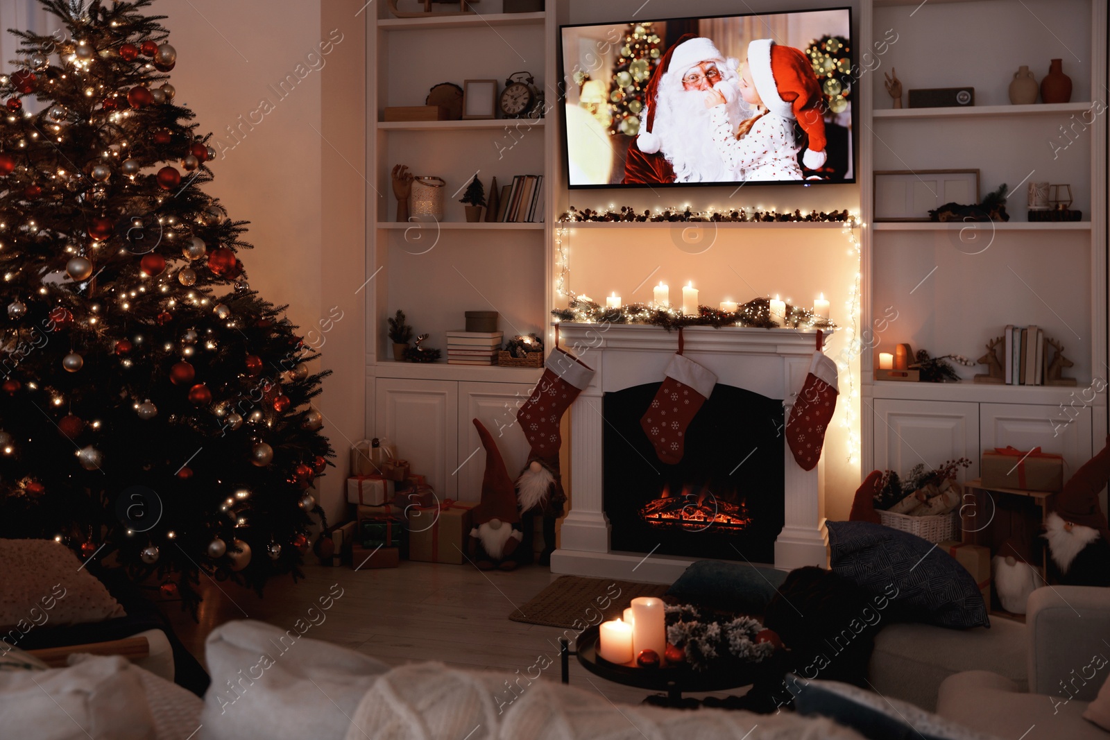 Photo of TV set with Christmas movie above fireplace in cosy room. Winter holidays atmosphere