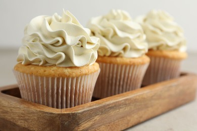 Photo of Tasty cupcakes with vanilla cream on light grey table, closeup