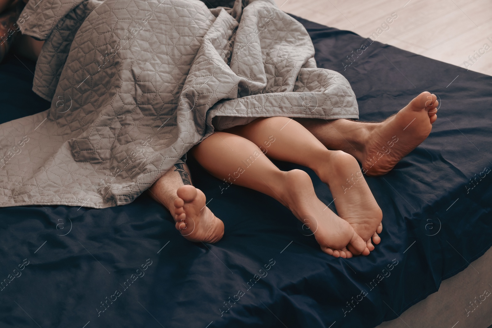 Photo of Passionate couple having sex on bed, closeup of legs