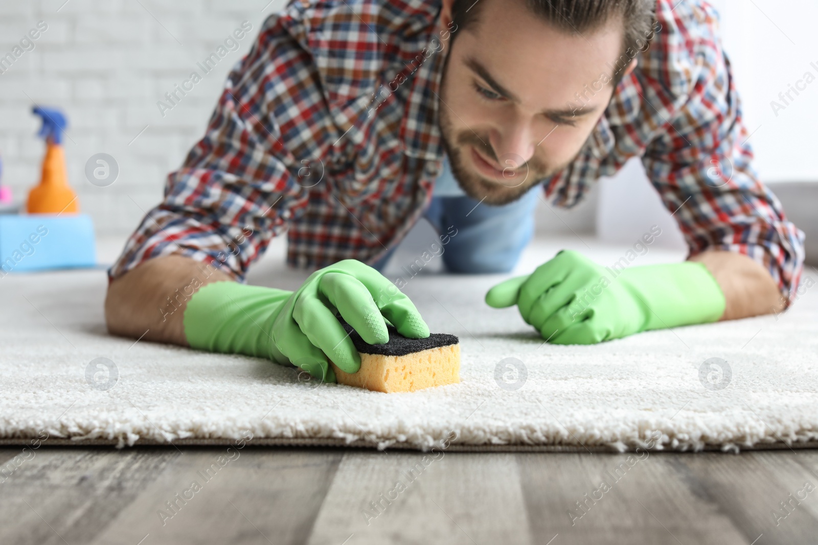 Photo of Young man cleaning carpet at home