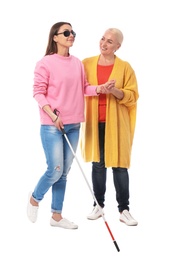 Mature woman helping blind person with long cane on white background